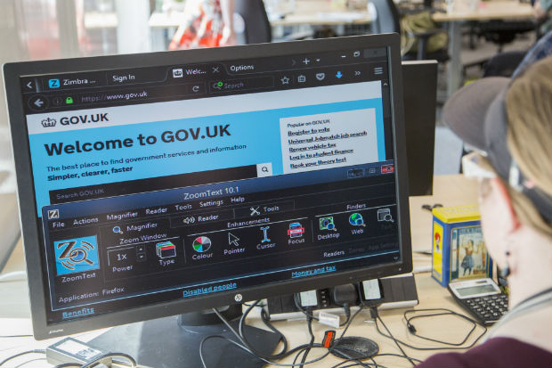 A low vision user's computer set up: large monitor at low resolution showing GOV.UK in browser with personalised colour settings. ZoomText preference panel is visible.