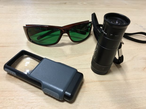 A Magnifying glass,, monocular and sunglasses with a special green tinted eye shields