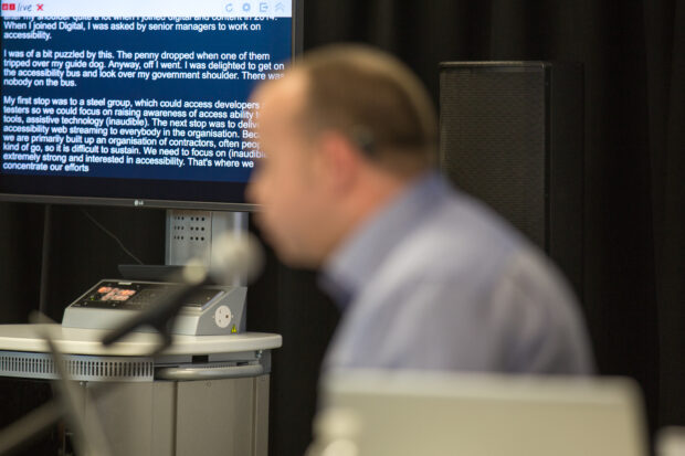 Blurry picture of a man's profile with a screen with a transcript in the background 