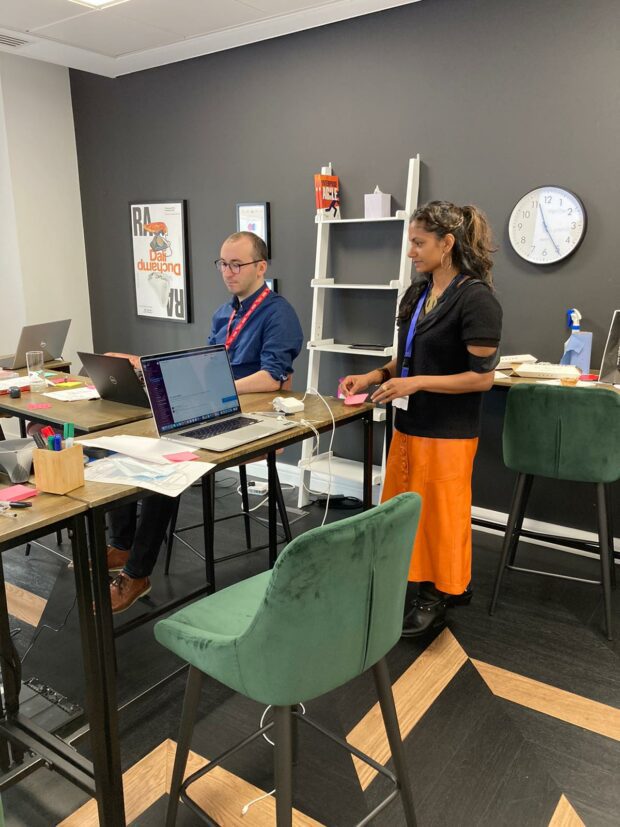 One developer sat at a high table in a meeting room testing the service using 1 of the accessibility personas with the User Researcher standing behind observing.