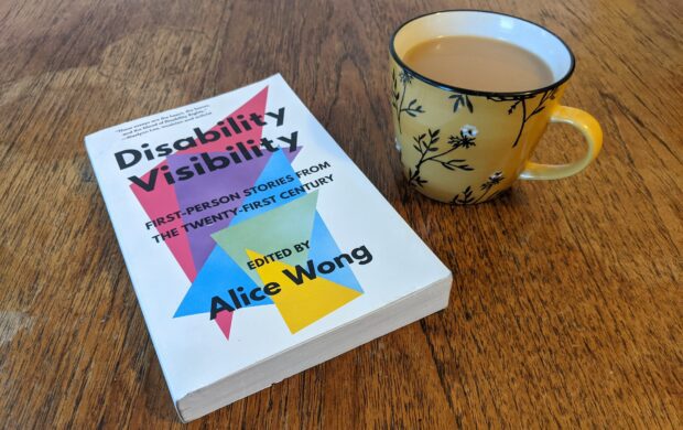 Copy of the book ‘Disability Visibility: First-person stories from the Twenty-first century’ edited by Alice Wong, on a wooden table next to a cup of tea.