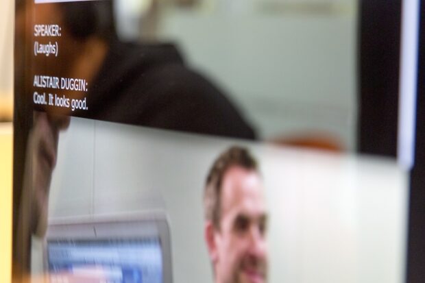 Photo of a man on a video screen, slightly blurred out, with captions displayed clearly on the same screen. 